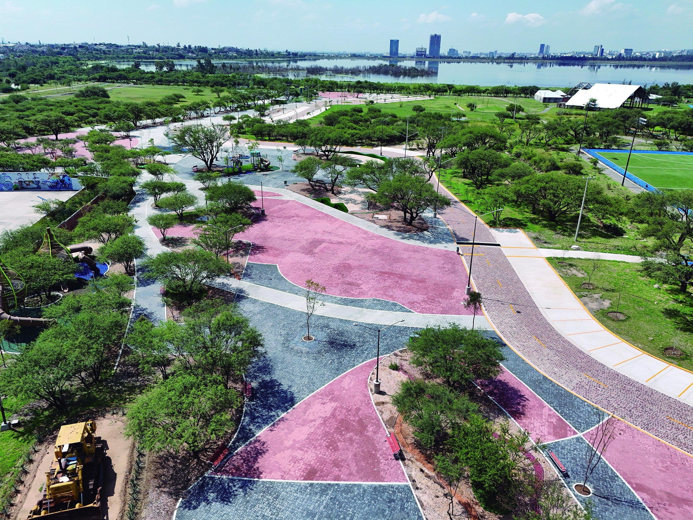 Vista aérea de un parque con andadores, ciclopista rosa y árboles.